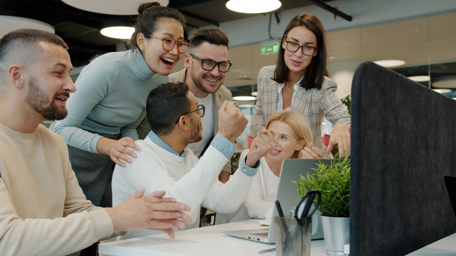 A happy, diverse team of company staff celebrating together in an office